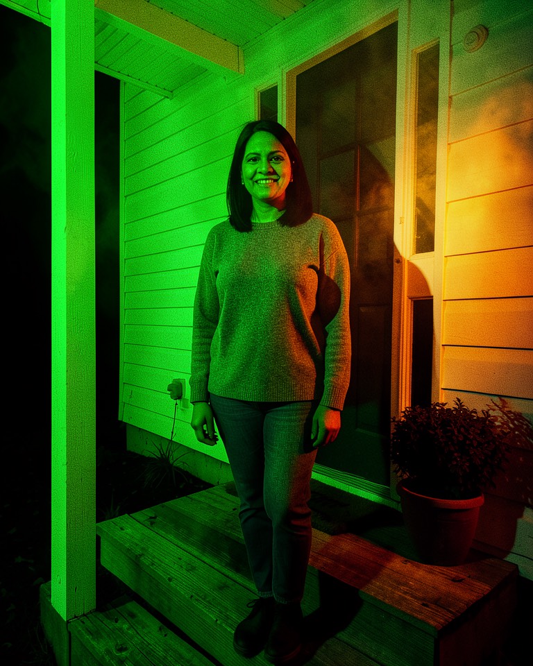 Halloween photo editor example: the woman on the porch relit at night with green light from the left and orange light from the right